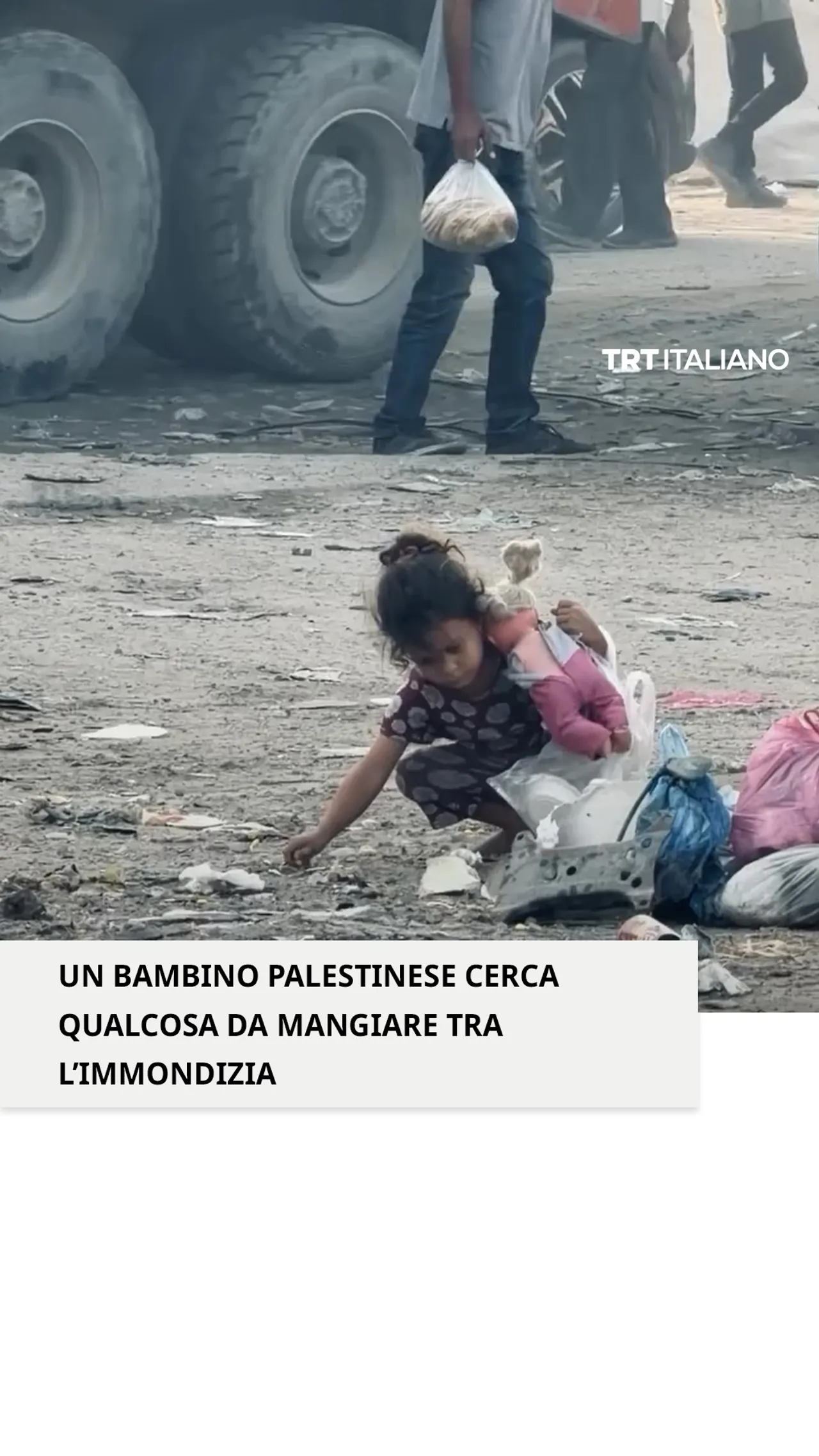 Un bambino palestinese cerca qualcosa da mangiare tra l'immondizia