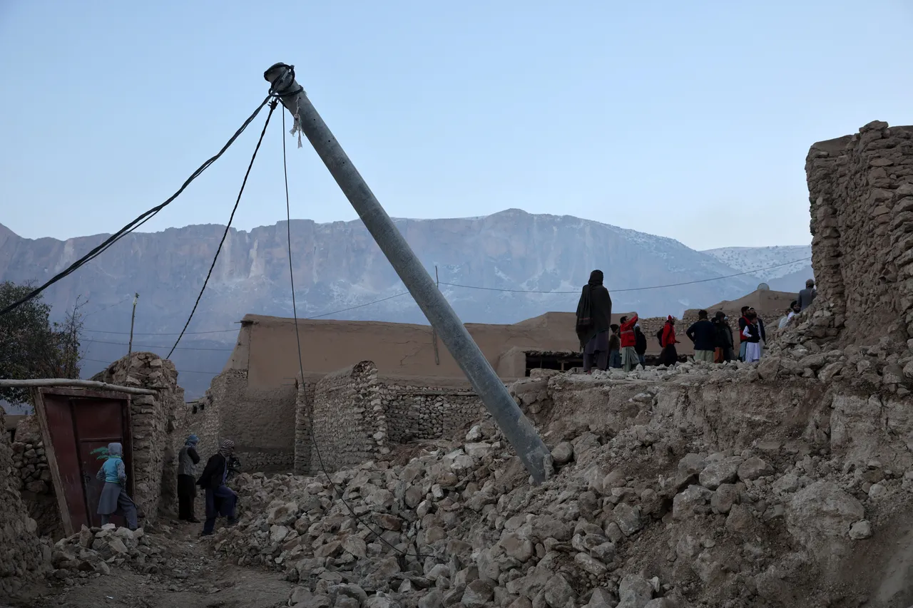 People stand amidst the debris of damaged houses following a recent earthquake in Marmul district