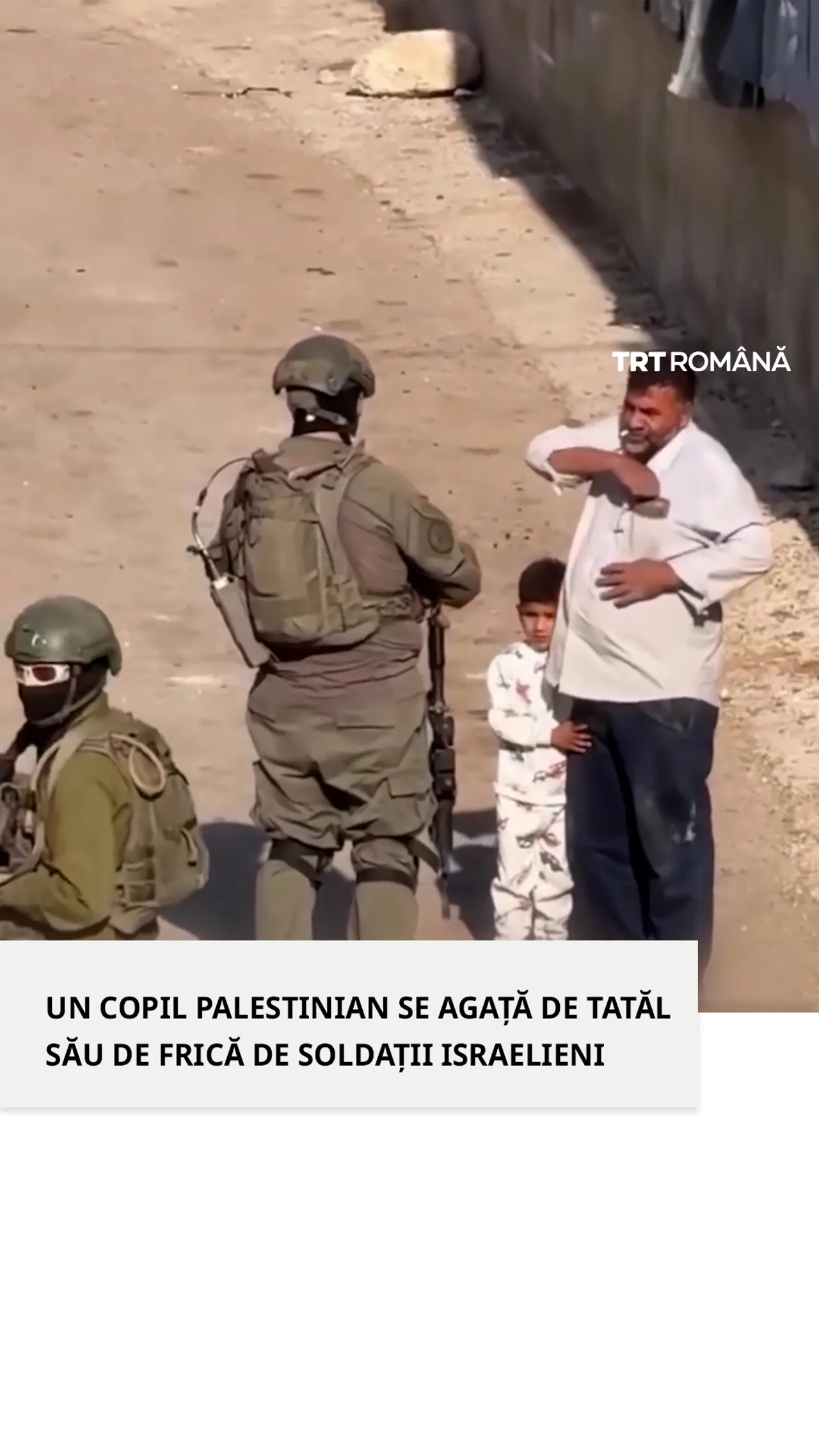 Un copil palestinian se ține de tatăl său de frică în fața unui soldat israelian