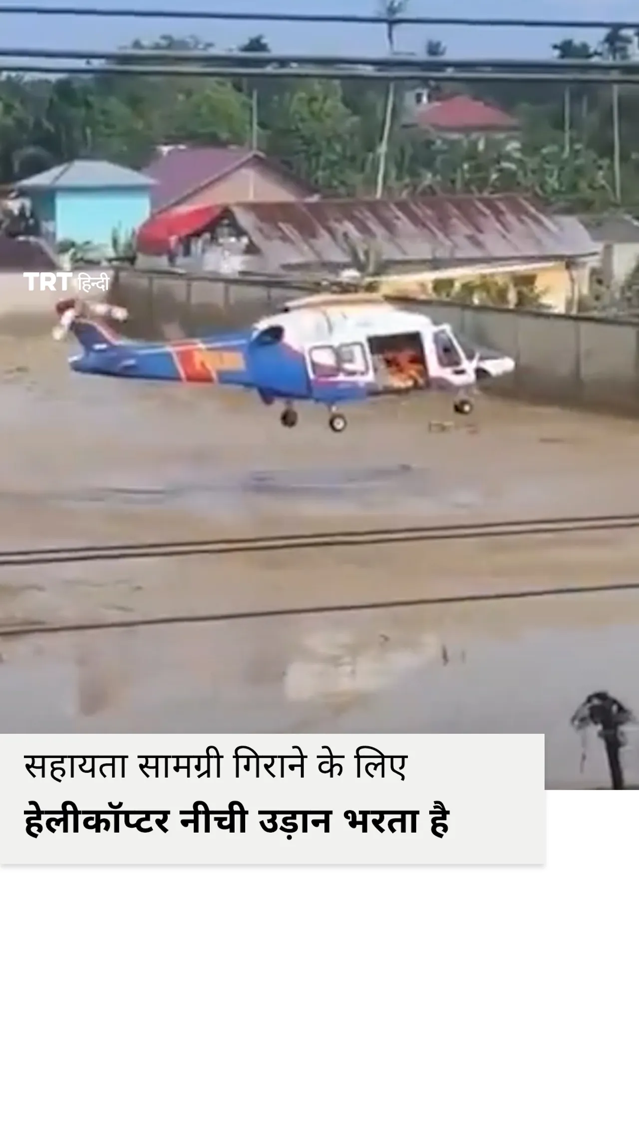 बाढ़ पीड़ितों के लिए सहायता सामग्री गिराने के लिए हेलीकॉप्टर नीची उड़ान भरता है