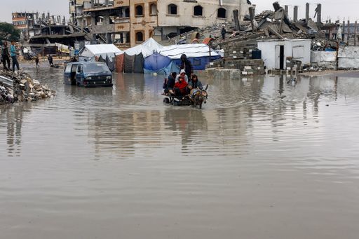 Displaced Palestinians ride a donkey-drawn cart on a rain-flooded street in Gaza City, December 12, 2025.
