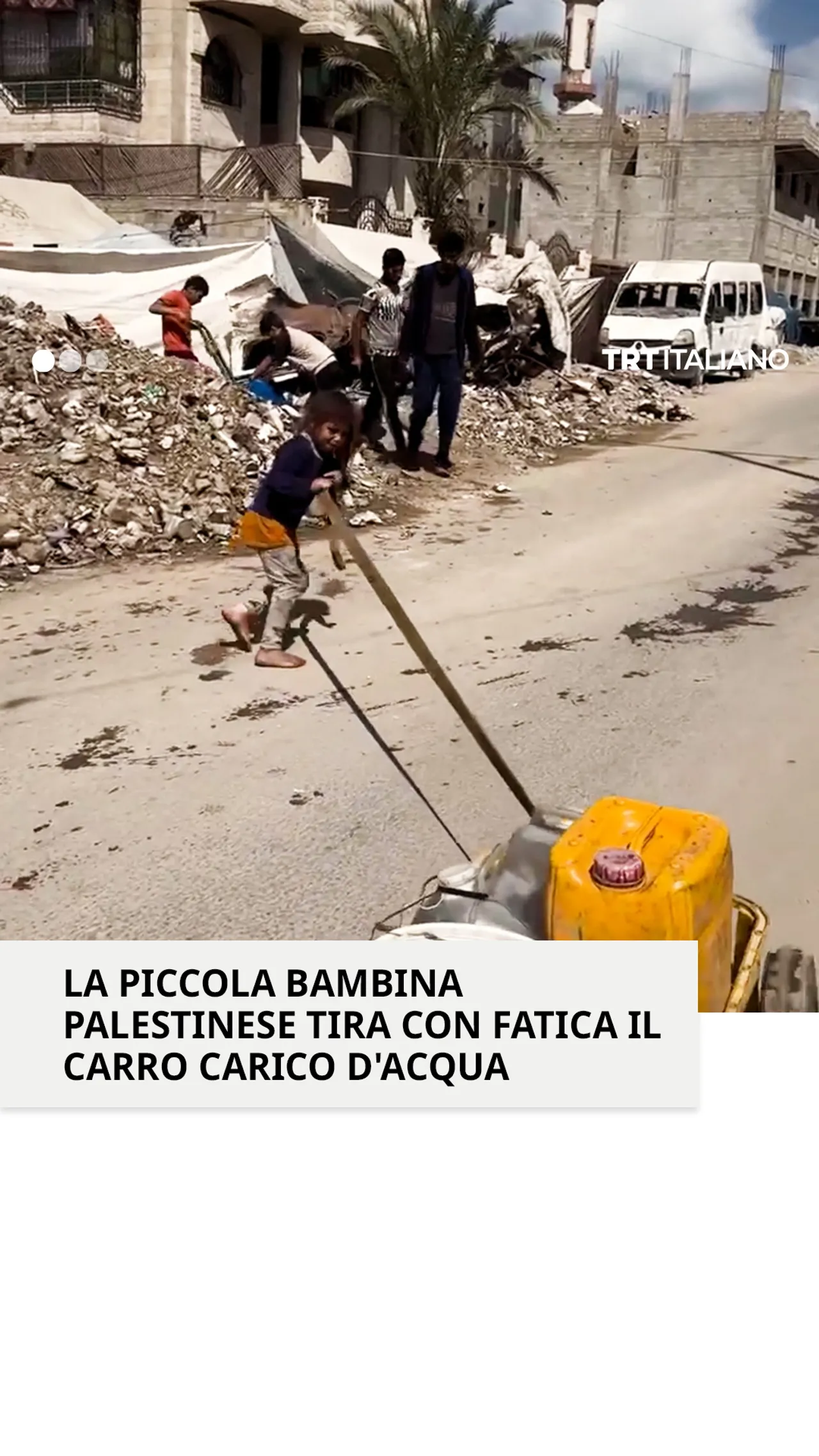 Una bambina palestinese fatica a trascinare un carretto carico d'acqua