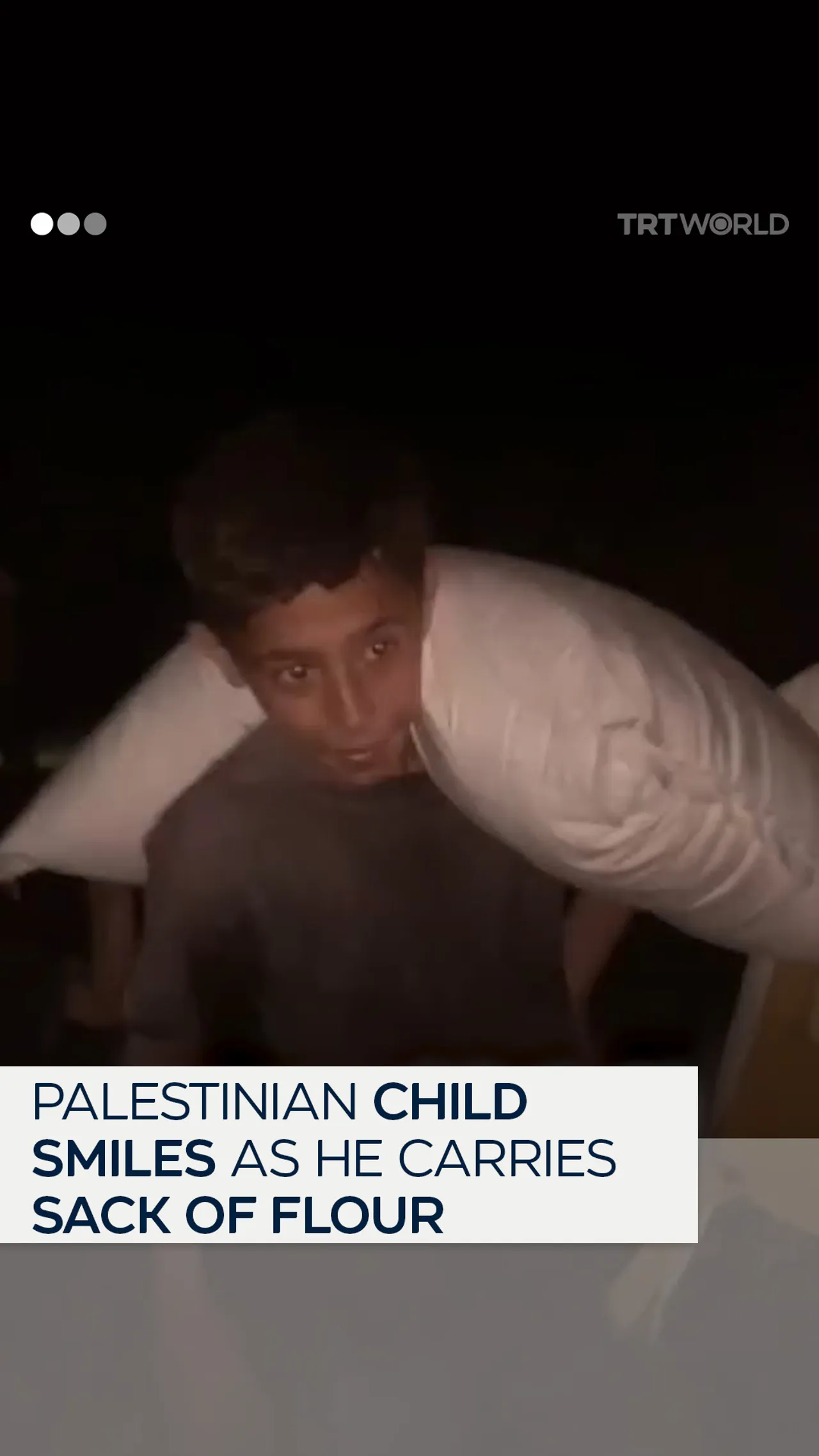 Palestinian child smiles as he carries a sack of flour back to his family