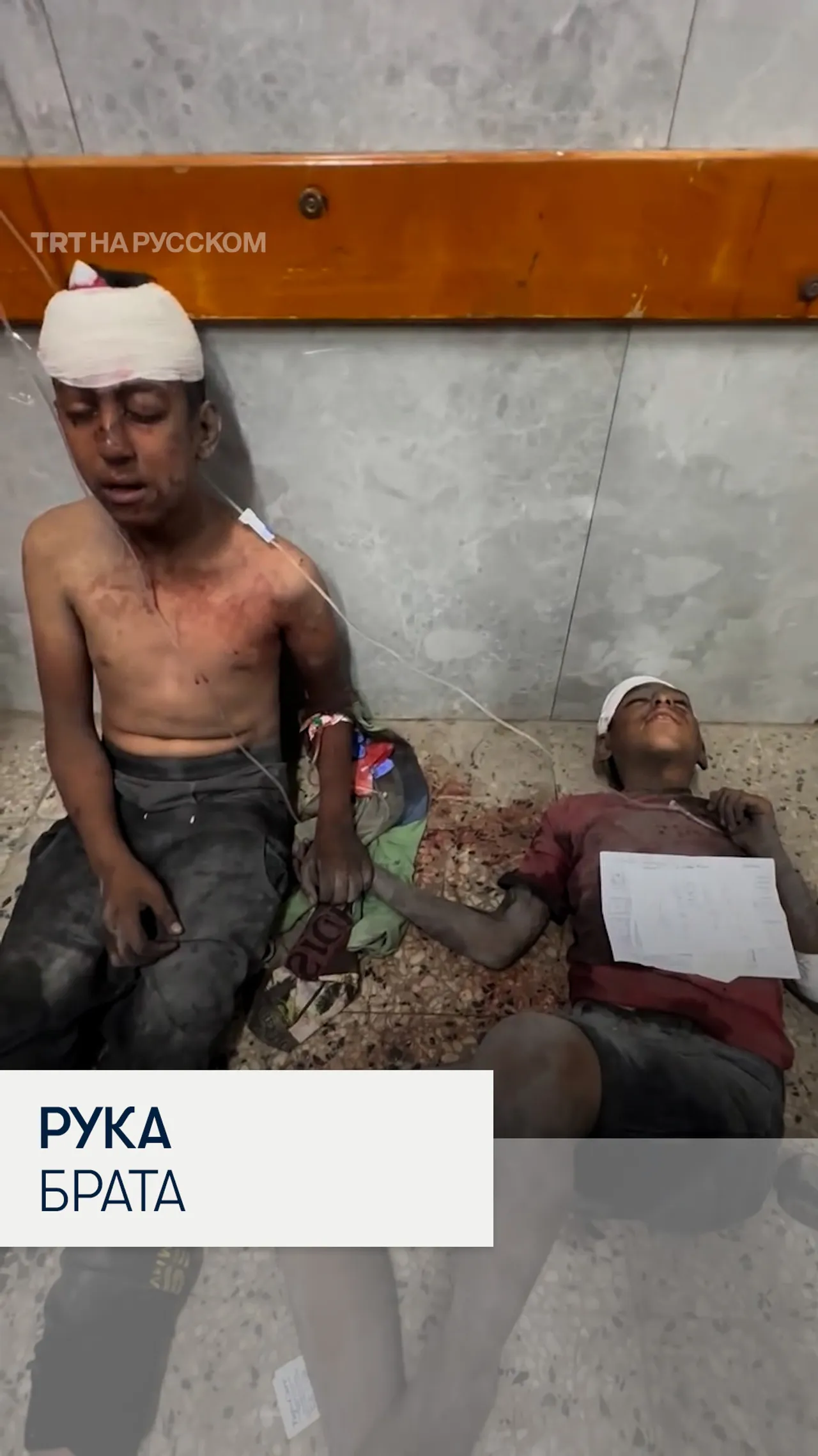 Раненый палестинский мальчик держит за руку брата в больнице Газы