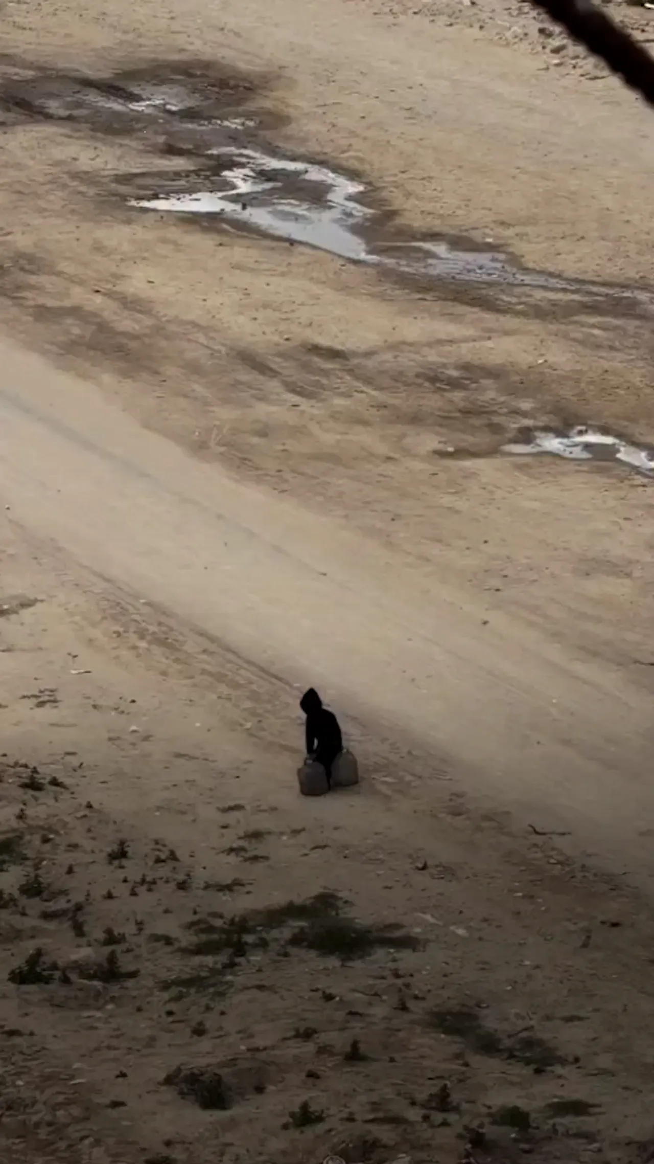 Seorang anak Palestina berjalan sendirian membawa beban berat