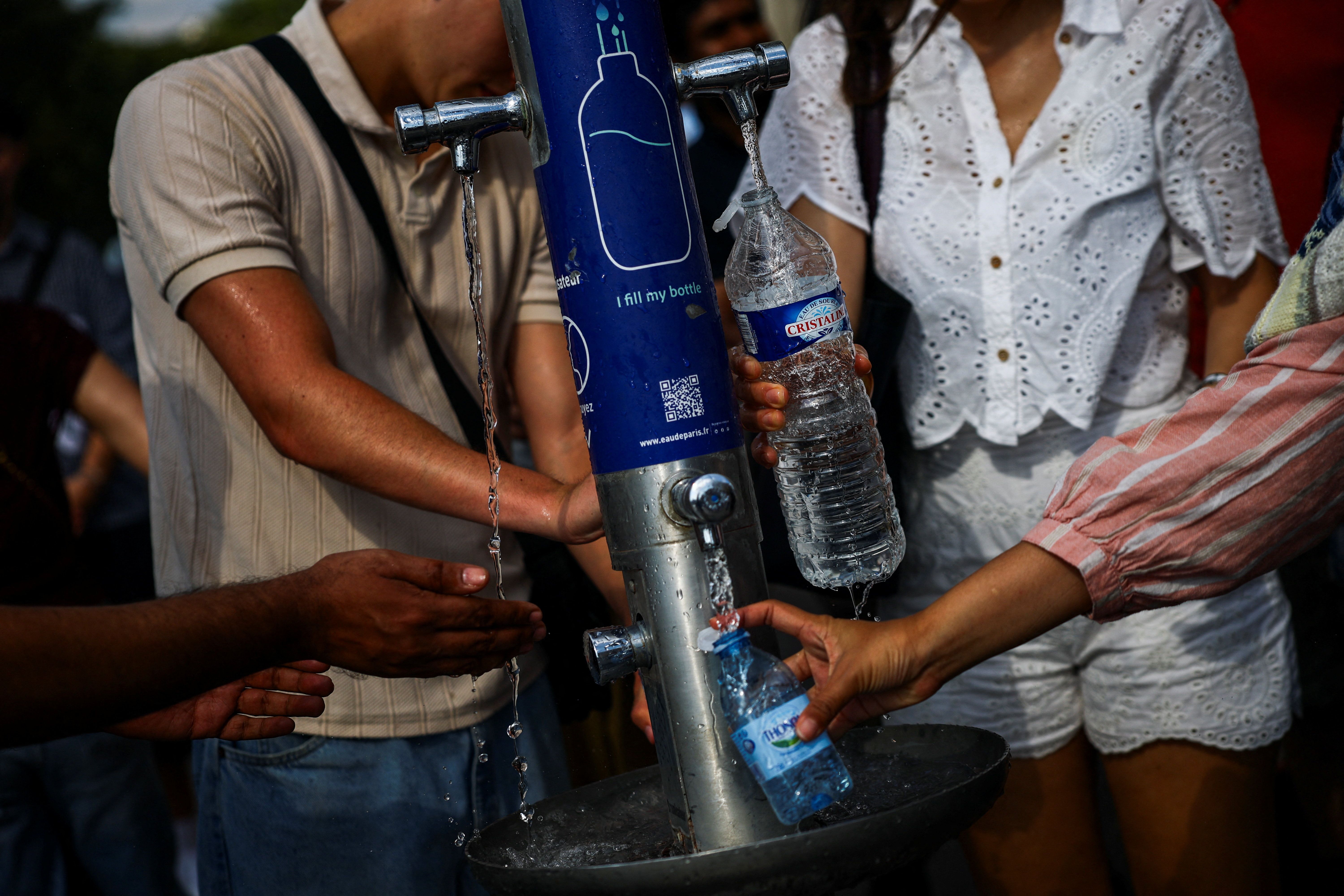 People filling water bottles from a fountain in Paris during the June 2026 heatwave