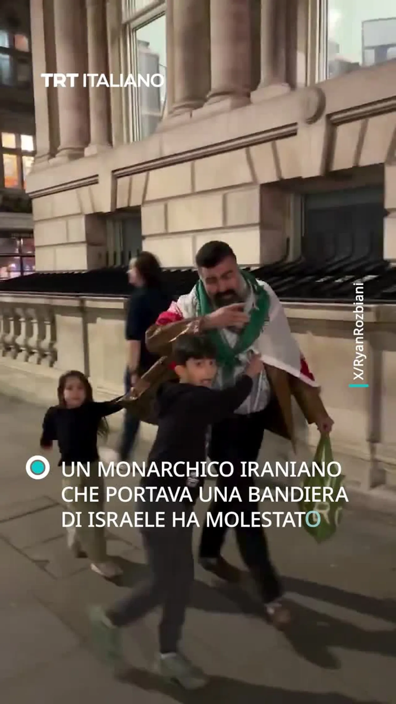 Un monarchico iraniano con una bandiera di Israele molesta un padre con i figli